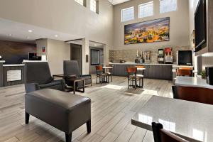 a lobby with chairs and tables and a bar at SureStay Plus Hotel by Best Western Tulsa East in Tulsa