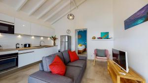 a living room with a couch and a kitchen at Les maisons Cane in Sainte-Rose