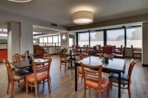 Drury Inn & Suites Evansville East في إيفانسفيل: غرفة طعام مع طاولات وكراسي ونوافذ