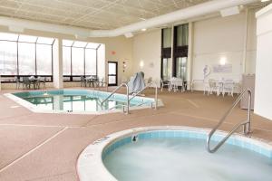a pool in a room with tables and chairs at Drury Inn & Suites St. Louis Airport in Edmundson