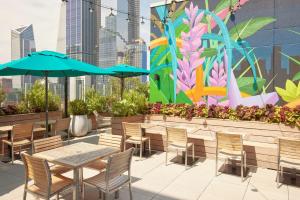 une terrasse avec des tables et des chaises ainsi qu'une fresque murale. dans l'établissement Arlo Midtown, à New York