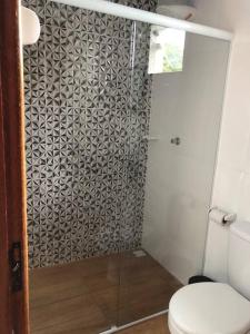 a bathroom with a shower with a toilet and a glass door at Chalé das Montanhas in Caparaó Velho