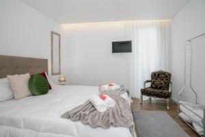a bedroom with a white bed and a chair at City Glow House in Ponta Delgada