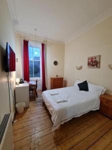 Dormitorio con cama, escritorio y TV en Haymarket Station Rooms, en Edimburgo