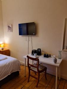 Habitación con cama, mesa y TV en la pared. en Haymarket Station Rooms, en Edimburgo
