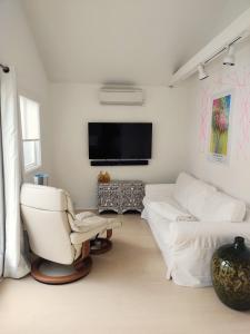 un soggiorno con mobili bianchi e TV a schermo piatto di Venice Canals & Beach Guest House a Los Angeles