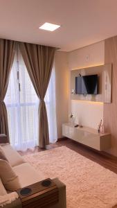 uma sala de estar com um sofá e uma televisão na parede em Elegante Apartamento, com ótima localização, na principal avenida de entrada em Bagé em Bagé
