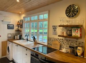 a kitchen with a sink and a clock on the wall at Cuckoo Cabin, Tyn Y Cwm in Scyborycoed