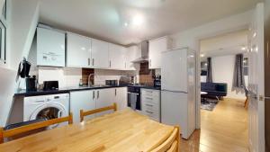 a kitchen with white cabinets and a wooden table at Spacious Duplex Apartment in London