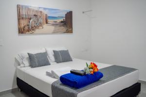 uma cama branca com uma almofada azul e flores em El Oscar Hotel em Medellín