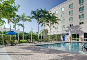 a swimming pool in front of a building with palm trees at Holiday Inn Express & Suites Miami Kendall, an IHG Hotel in Kendall