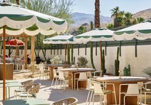a patio with tables and chairs and umbrellas at Life House, Palm Springs in Palm Springs