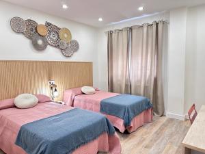 2 Betten in einem Zimmer mit rosa und blau in der Unterkunft La Casita de Tita in Salamanca