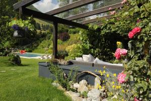 a garden with a bench and flowers and a pool at Hotel Saalbacher Hof in Saalbach-Hinterglemm