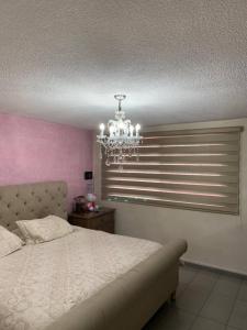 1 dormitorio con cama y lámpara de araña en Casa completa para 8 en Coacalco SuperB, en Ciudad de México