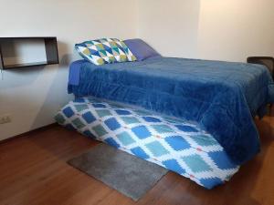 a bed with a blue comforter and a pillow at Hermoso MiniDepa de Estreno en La Molina in Lima