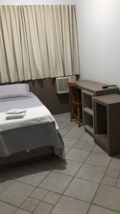 1 dormitorio con cama, escritorio y escritorio en Hotel Parati, en Morro da Fumaça
