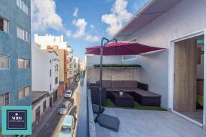 a balcony with a table and an umbrella on a building at Playa Verde Las Canteras in Las Palmas de Gran Canaria