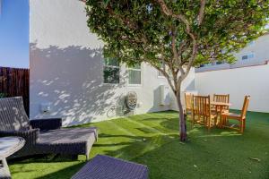 a lawn with chairs and a tree in a yard at Lovely White Beach House in Redondo Beach
