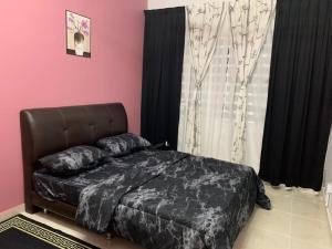 a bedroom with a bed with a black bedspread at ALEENA STAYCATION @ APARTMENT TOK PELAM PANTAI BATU BURUK in Kuala Terengganu