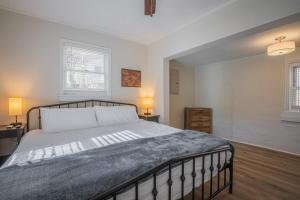 a bedroom with a large bed and two windows at Cara's Cottage 2 miles from Sanford Stadium in Athens