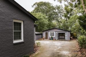 a black brick house with a driveway and a garage at Greenway Garage with Firepit in Athens