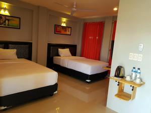Cette chambre d'hôtel comprend 2 lits avec des rideaux rouges. dans l'établissement CHEAGIA Resort at Sitinjo near Sidikalang, à Hutamanik
