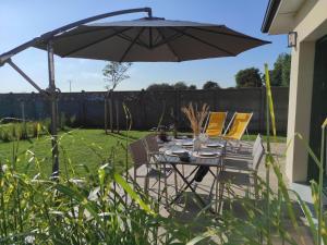 einen Tisch und Stühle unter einem Regenschirm im Hof in der Unterkunft Charming cottage only 8 minutes from Etretat in Bordeaux-Saint-Clair