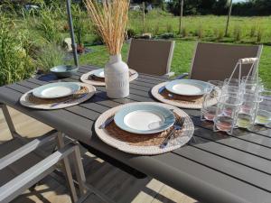 einen Picknicktisch mit Tellern, Gläsern und einer Vase in der Unterkunft Charming cottage only 8 minutes from Etretat in Bordeaux-Saint-Clair