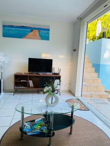 ein Wohnzimmer mit einem Glastisch und einem TV in der Unterkunft Le Cocon de l'Oranger in Le Moule