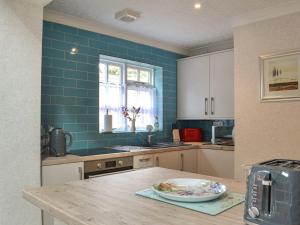 uma cozinha com uma mesa e uma parede de azulejos azuis em The Stables em Hedon