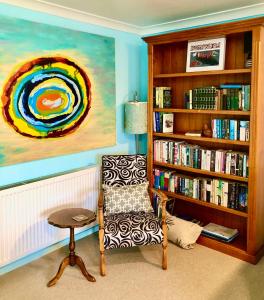 Una habitación con una silla y una estantería con libros. en Butterfield Beach Studio Car petrol and breakfast provisions included, en Half-moon Bay