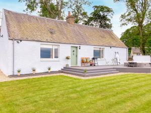 a white cottage with a lawn in front of it at South Riccalton Farm Cottage in Oxnam