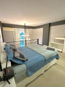 1 dormitorio con cama con sábanas azules y ventana en Saint Sebastian Flat 716 - Com Hidro! até 3 pessoas, Duplex, no centro en Jaraguá do Sul