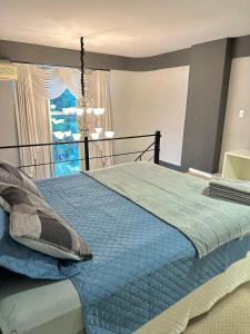 um quarto com uma cama com um edredão azul e uma janela em Saint Sebastian Flat 716 - Com Hidro! até 3 pessoas, Duplex, no centro em Jaraguá do Sul