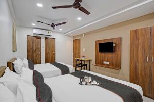 a hotel room with two beds and a flat screen tv at OYO Collection O Hotel Infini Palace in Surat