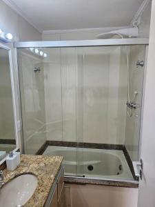 a bathroom with a shower and a sink and a tub at Flat Capitânia Varam 143 Pitangueiras in Guarujá
