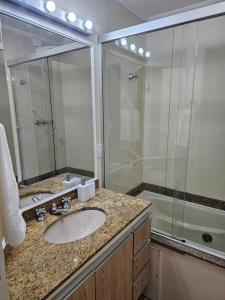 a bathroom with a sink and a shower at Flat Capitânia Varam 143 Pitangueiras in Guarujá