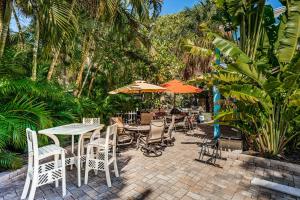 un patio al aire libre con mesas, sillas y sombrillas en Blue Water Beachside Villa 1 en Clearwater Beach