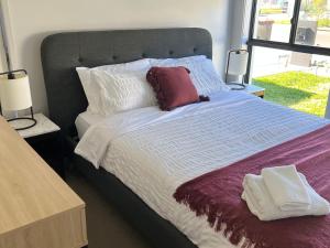 Una cama con almohadas blancas y rojas. en A Private Ensuite with AC and TV en Austral