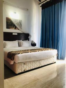 1 dormitorio con 1 cama grande y cortinas azules en Ocean Pearl Cottage en Ahungalla