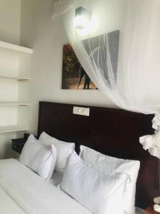 1 dormitorio con 1 cama con almohadas blancas en Ocean Pearl Cottage en Ahungalla