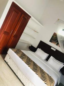 1 dormitorio con 1 cama y puerta de madera en Ocean Pearl Cottage, en Ahungalla