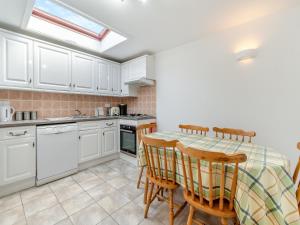 a kitchen with white cabinets and a table and chairs at Clover Cottage- Uk45595 in Verwick