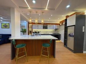 a kitchen with a large island with two green bar stools at WATERFRONT 3BR APT W/FREE PARKIN WiFi NETFLIX POOL in Lagos