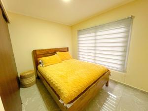 ein Schlafzimmer mit einem Bett mit gelben Laken und einem Fenster in der Unterkunft Cabañas Maravillas de Quetroleufu in Pucón