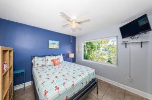 a bedroom with a bed with a ceiling fan and a window at Blue Water Beachside villa 2 in Clearwater Beach