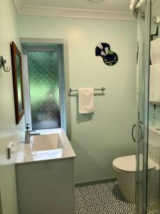 Un baño con lavabo, inodoro y ventana. en Butterfield Beach Studio Car petrol and breakfast provisions included, en Half-moon Bay