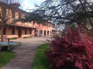 a building with a brick walkway next to a pink bush at Agriturismo Da Ninoti in Treviso
