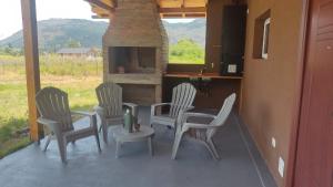 a patio with four chairs and a stone fireplace at Rincón Bonito in El Hoyo